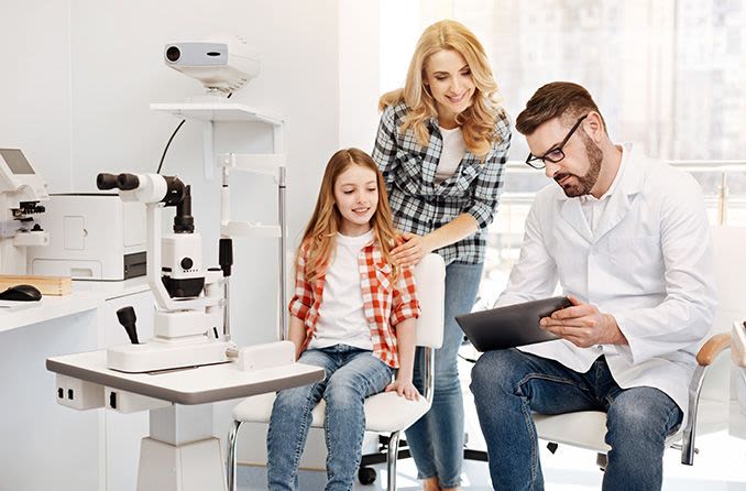 woman and child looking at eye exam results with doctor