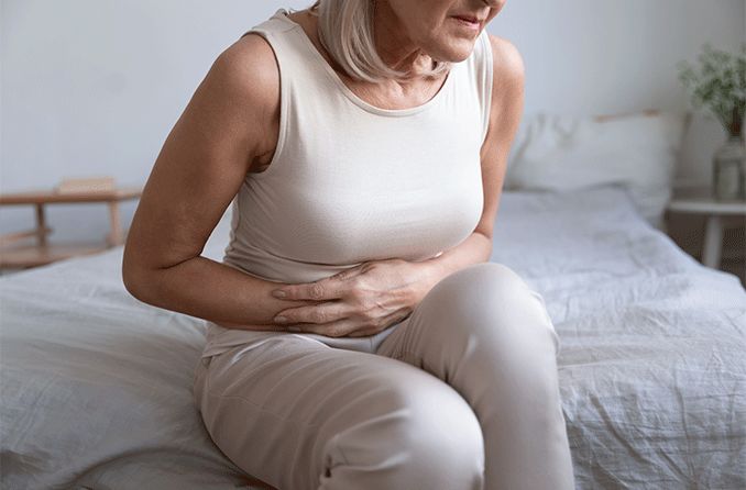 woman with poor gut health holding her stomach in discomfort
