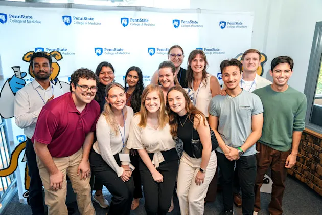 Students posing in front of a Penn State College of medicine sign.