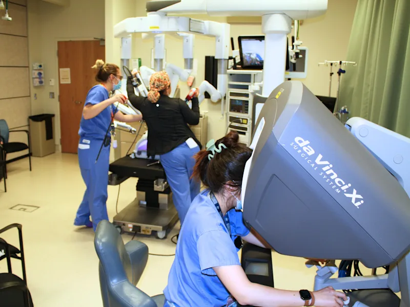 A person looks into a da Vinci Xi surgical system while two others use a different piece of equipment.