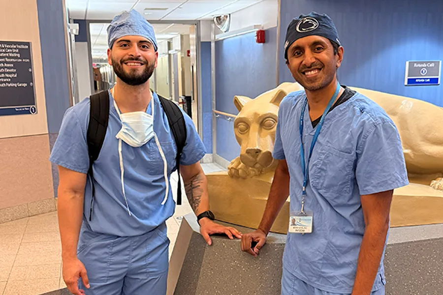 Medical student, Matt Hernandez, poses with his mentor, Dr. Nareev Goyal, beside a Penn State Nittany Lion statue