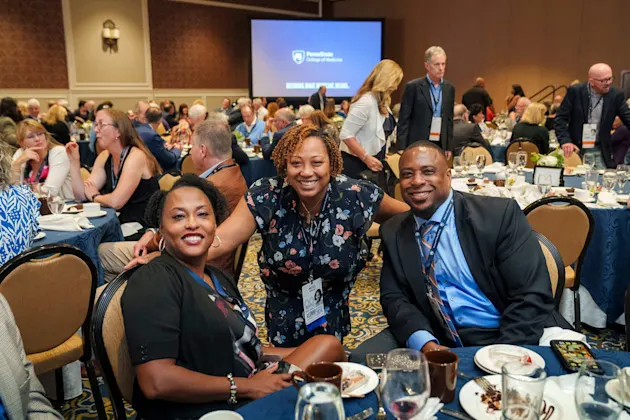 Three people posing together at a formal dinner