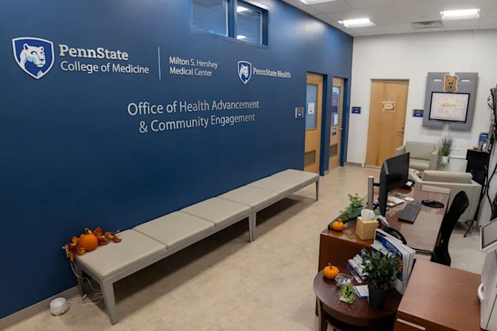 Inside of Office of Health Advancement & Community Engagement with a blue wall including Penn State marks and the offic ename