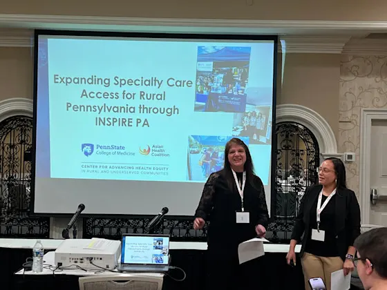 Two presenters stand before a screen titled 'Expanding Specialty Care Access for Rural Pennsylvania through INSPIRE PA.'