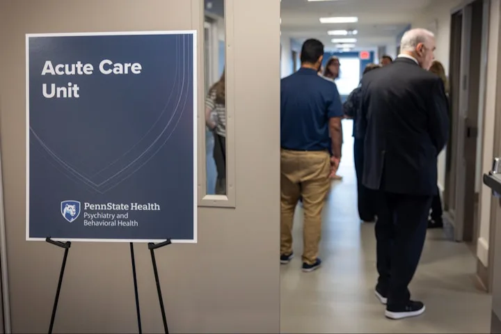 People mingle in a hallway with a sign that says Acute Care Unit and Penn State Health Psychiatry and Behavioral Health