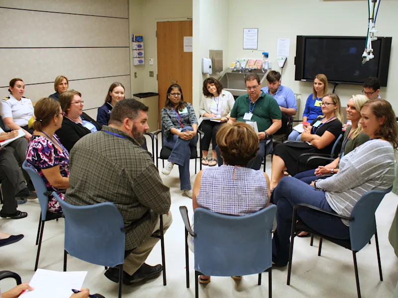 Healthcare educators gather around a manikin during a hands-on simulation exercise at the Simulation Instructor Course.
