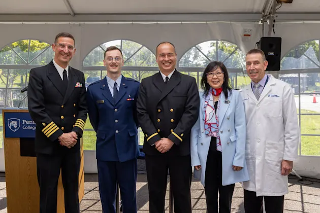 Two commissioned military officers flanked by College of Medicine leaders after the 2026 military commissioning ceremony