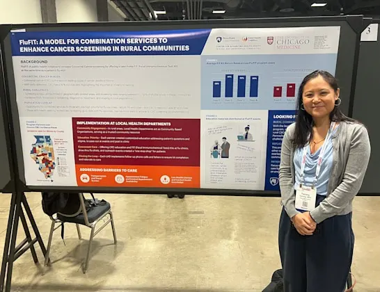 Woman stands beside a research poster on FluFIT, a model for combination cancer screening services in rural areas