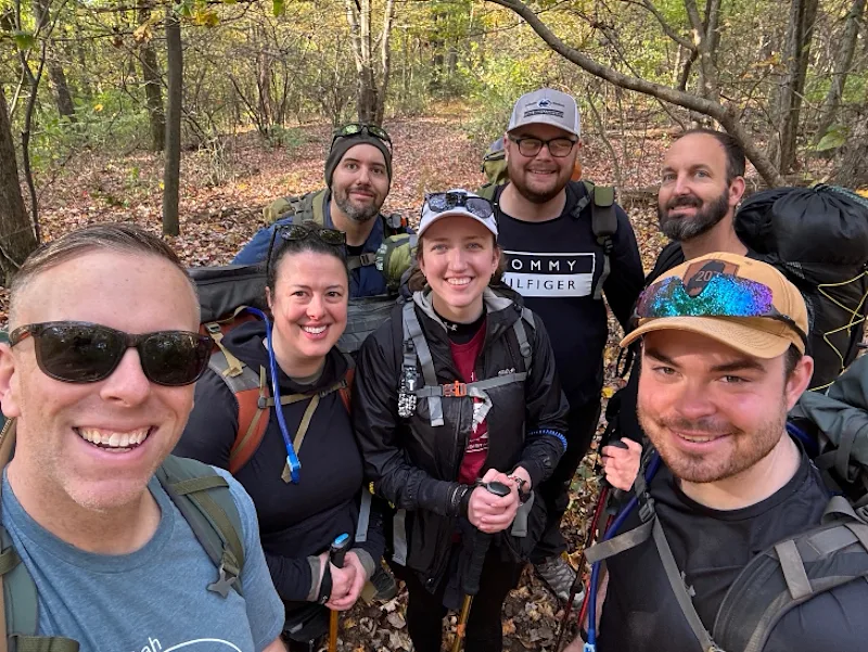Seven people pose for a selfie in the woods