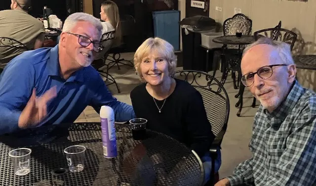 Three emeritus faculty members at a round outdoor table