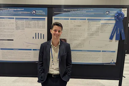 Medical student stands in front of two research posters