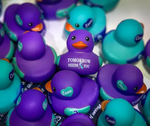 Close up of rubber ducks; the one in the middle has the words "Tomorrow Needs You."