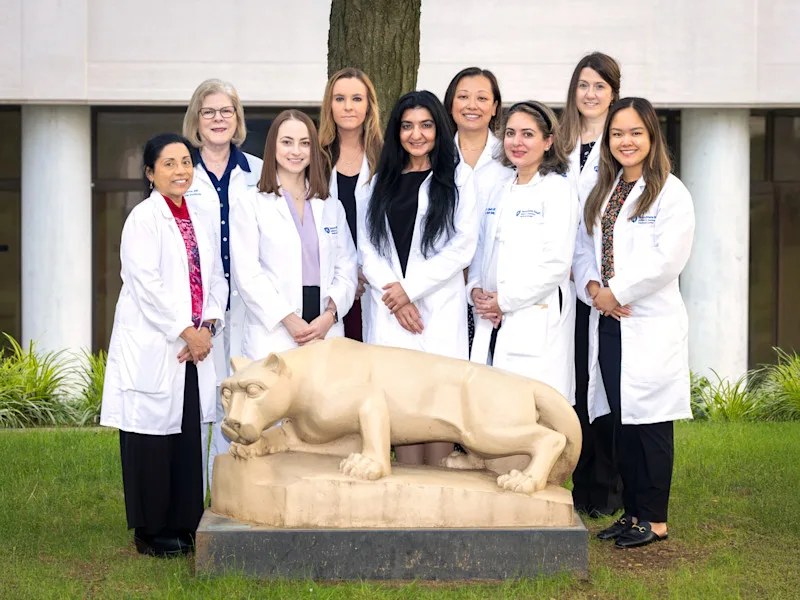 Nine women cardiologists in white coats; four seated in front and five standing in the back.