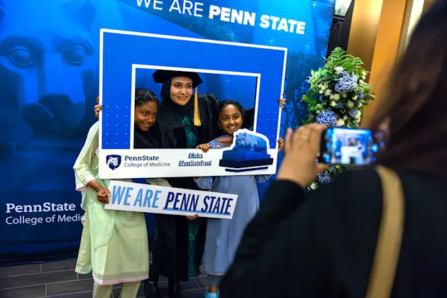A graduate and her nieces gets a photo with a Penn State frame