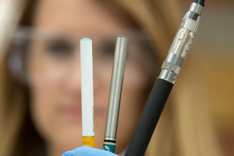 Scientists holds up three vaping and e-cigarette devices