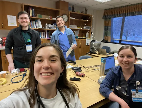Four residents on call, two seated and two standing behind, take a selfie