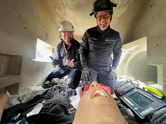 Two fellows wearing hard hats and gloves in a confined space during a training drill