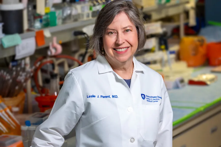 Leslie Parent stands in her lab in a white coat