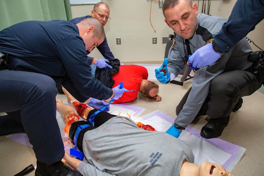 Emergency responders practice trauma care techniques using a high-fidelity manikin during simulation training.