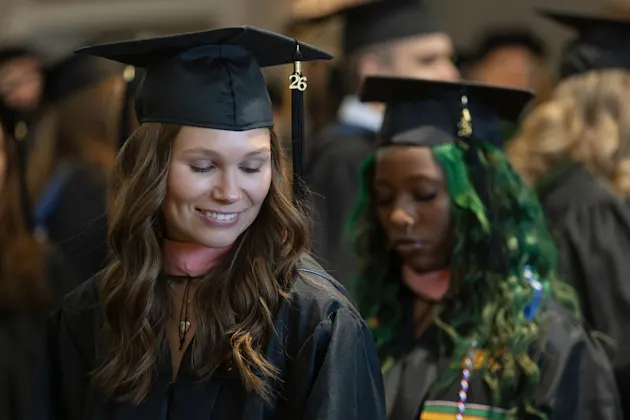 Sandra Crawford gets help with her hood from Mekele Chambers during commencement