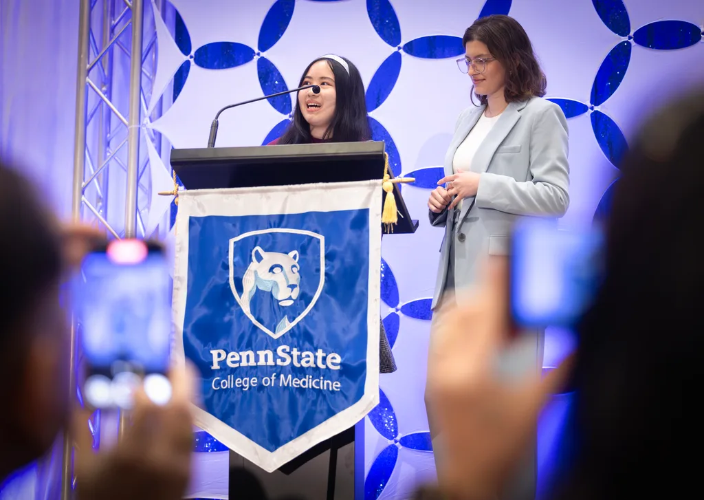 Angela Tran and Katrina Bakhl, co-class-presidents, make remarks behind a lectern with a College of Medicine banner