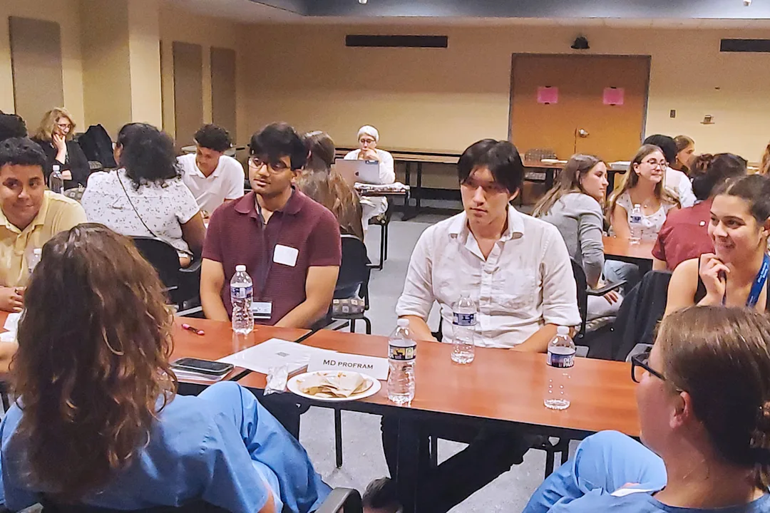 Program participants sitting at tables with medical students to discuss next steps during an educational career session