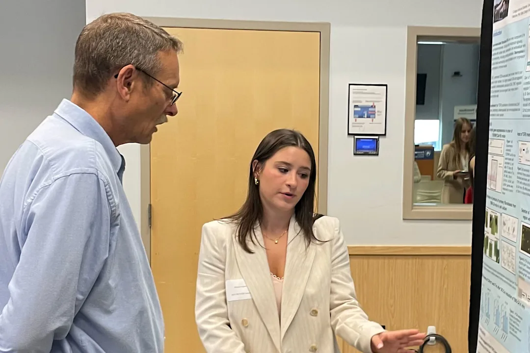 A program participant presents her research poster to a faculty member at the Poster Symposium
