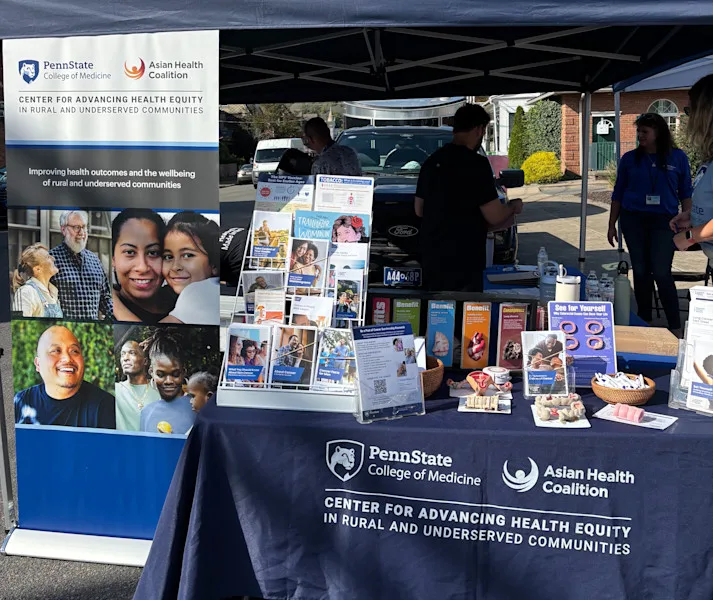 A CAHE-RUC table at an outdoor event setup with posters, pamphlets and giveaways