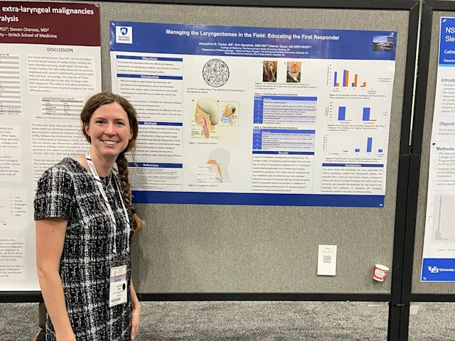 A medical student stands beside a research poster at a conference display