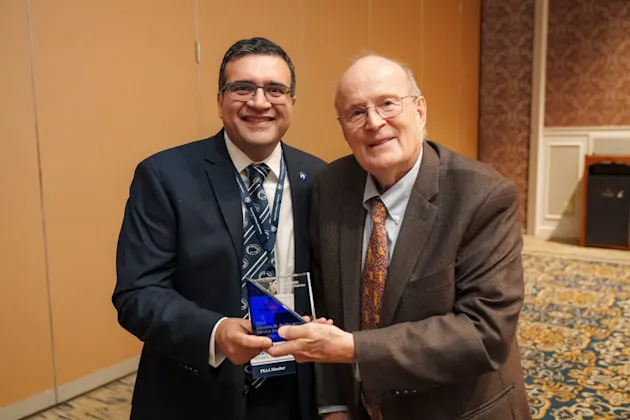 Two people posing with an award.