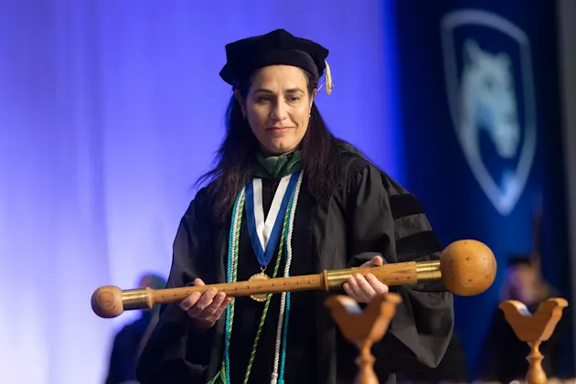 Dr. Emmanuelle Williams leads the commencement processional holding the mace.