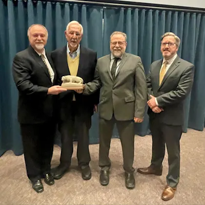 A group poses for a photo as a lion statue award is presented to the visiting professor.