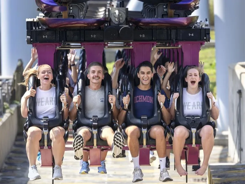 Four students on the Great Bear rollercoaster, with body harness restraints and feet dangling