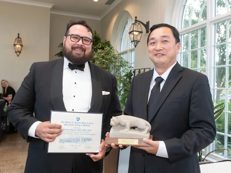 Dr. Christian Gluck accepts certificate and lion statue from fellowship program director Dr. Shawn Li at graduation.