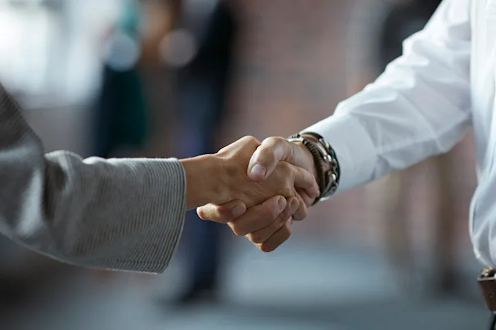 Two people shaking hands; just their arms and hands are visible