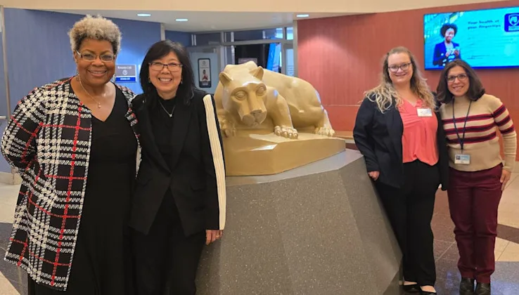 Four members of the center pose next to the Nittany Lion statue in the Hershey Medical Center rotunda