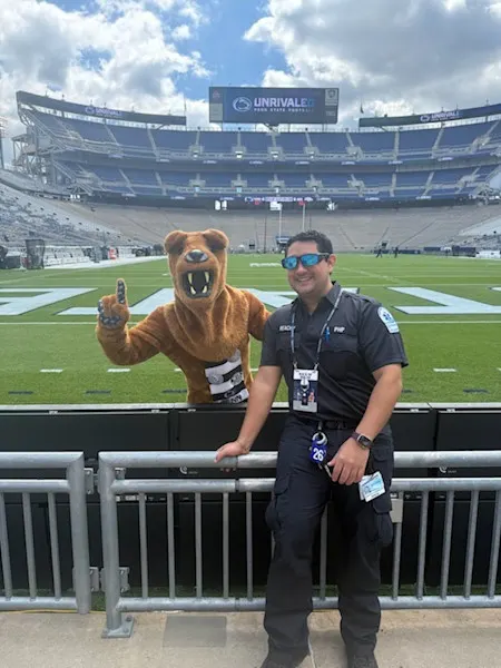 An EMS fellow poses with the Nittany Lion mascot, who is giving a No. 1 hand sign, inside Beaver Stadium