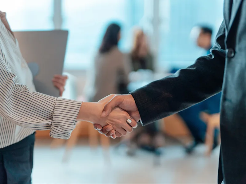 Two people shaking hands in a business environment