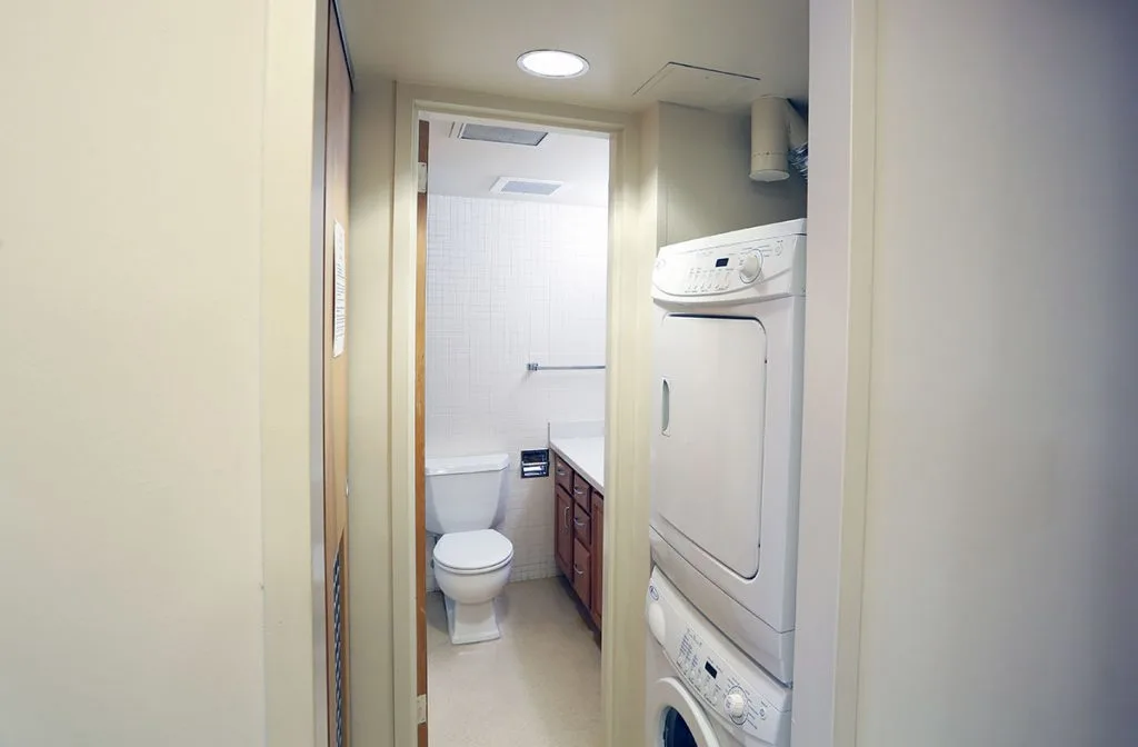 Bathroom and laundry area at University Manor East shows a stacked washer and dryer and a bathroom visible beyond