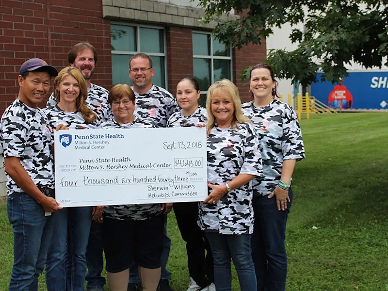 Employees of Sherwin Williams hold a check made out to Penn State Health