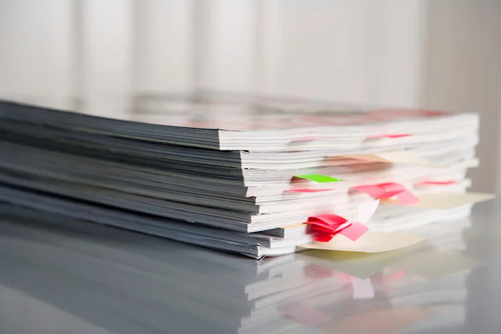 A stack of publications on a table with page markers sticking out
