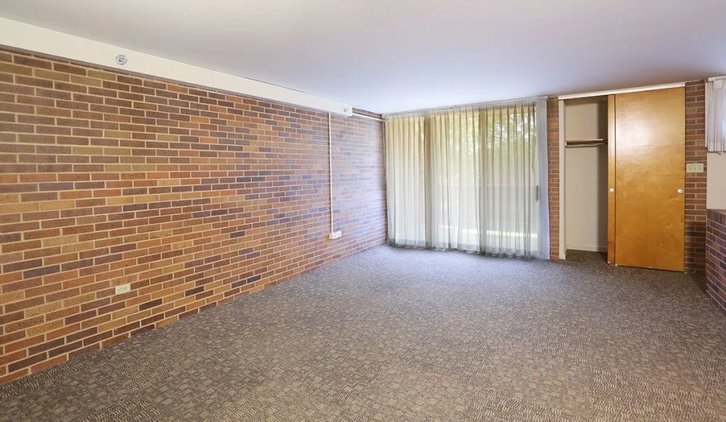 Living area at University Manor East with a door leading outside to a balcony or patio as well as a closet door.
