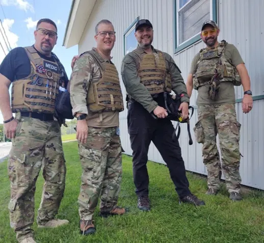 Four fellows wear tactical gear outdoors during a drill