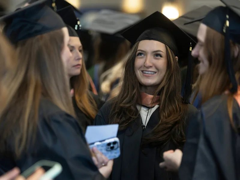 A student smiles as she and three others wait for commencement to begin