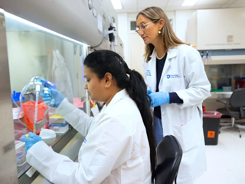 Dr. Giselle Sholler looks over the shoulder of a research technologist working in Sholler's lab