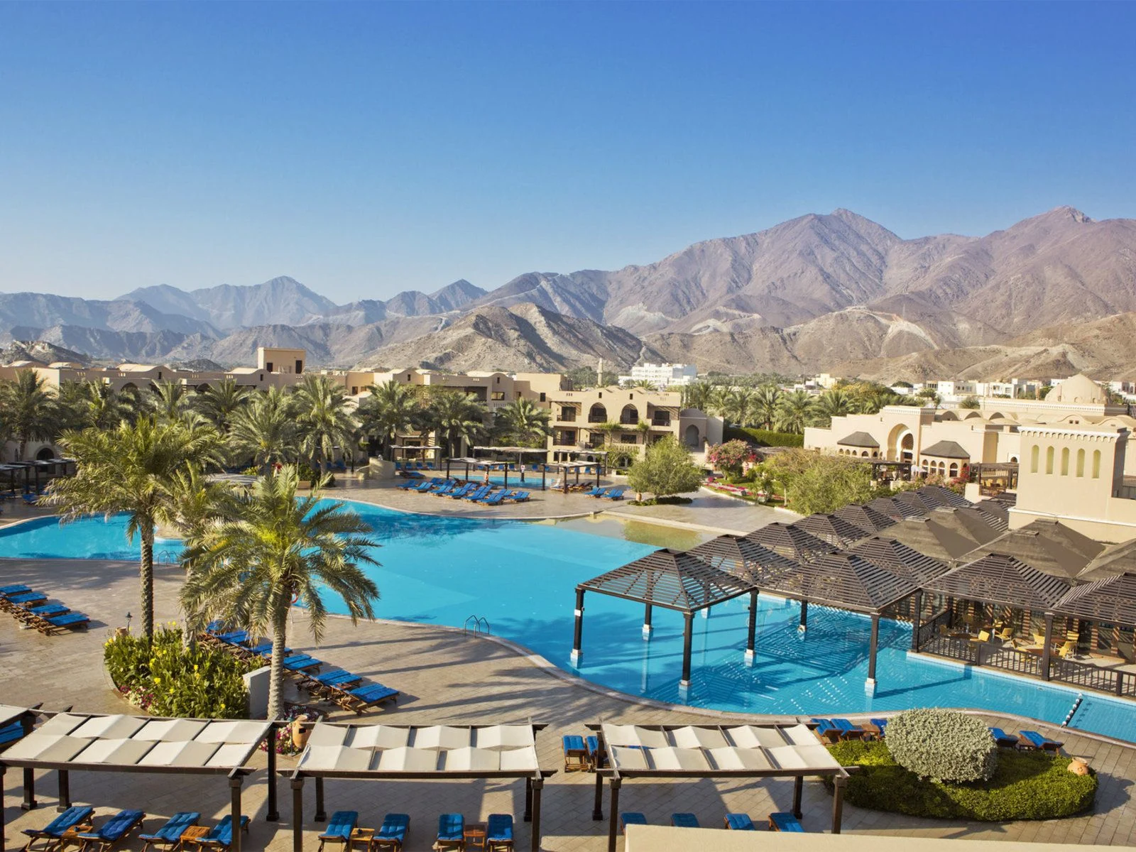 Pool area of Iberotel Miramar Al Aqah Beach Resort with mountains in the background