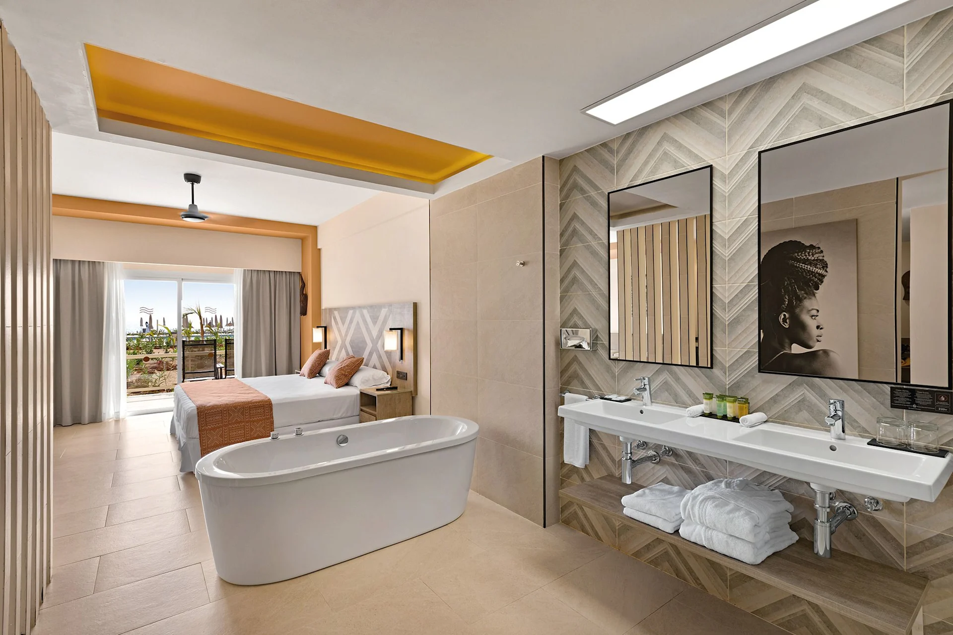 hotel room with bed, bath tub in the middle of the room, double sink and view to the balcony