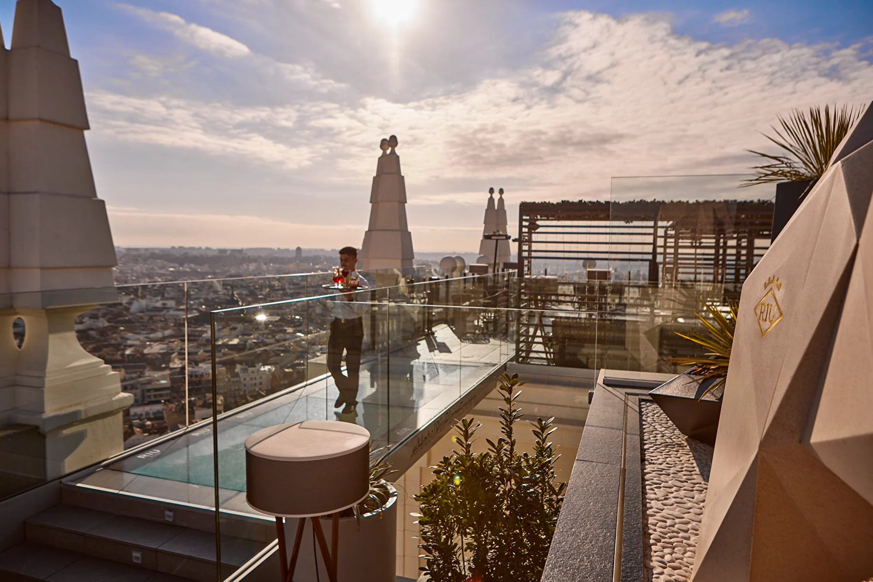 rooftop bar with view on Madrid and a waiter crossing a bridge made of glass