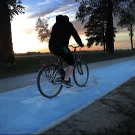 Das Bild zeigt einen Fahrradfahrer auf einem selbstbeleuchteten Radweg während der Dämmerung.