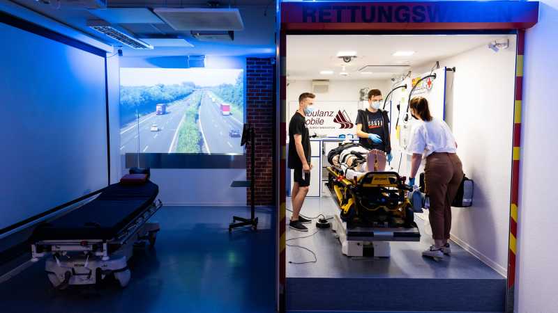 Drei Schüler üben den Krankentransport im einem Simulationszentrum. 